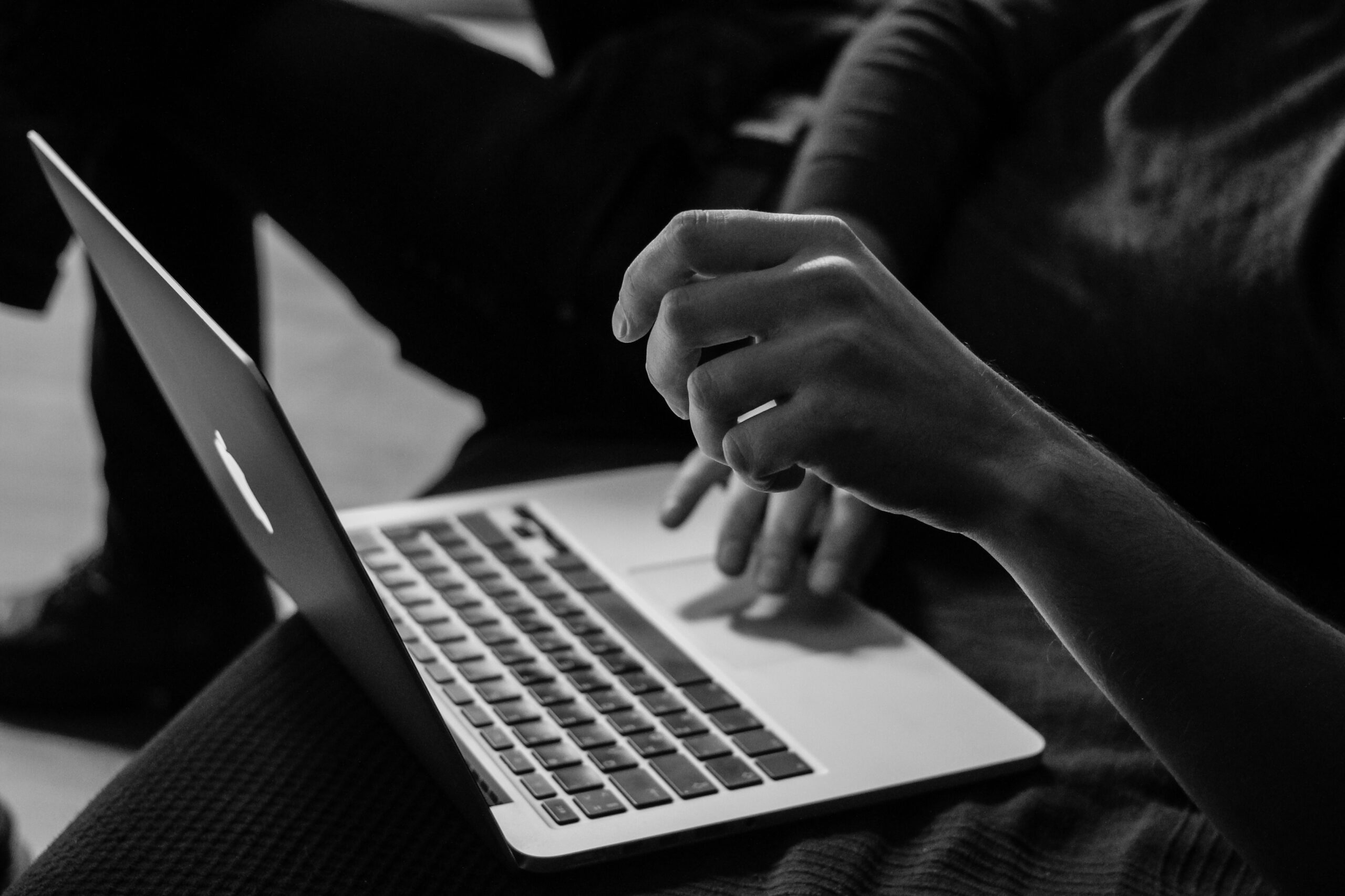 black and white photo of woman working on MacBook.